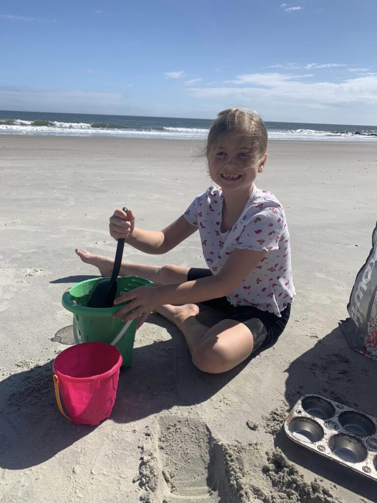 girl playing in sand near the ocean