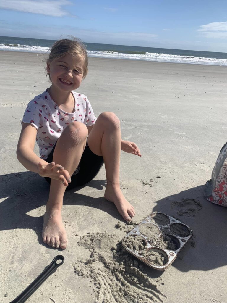 girl playing in sand near the ocean