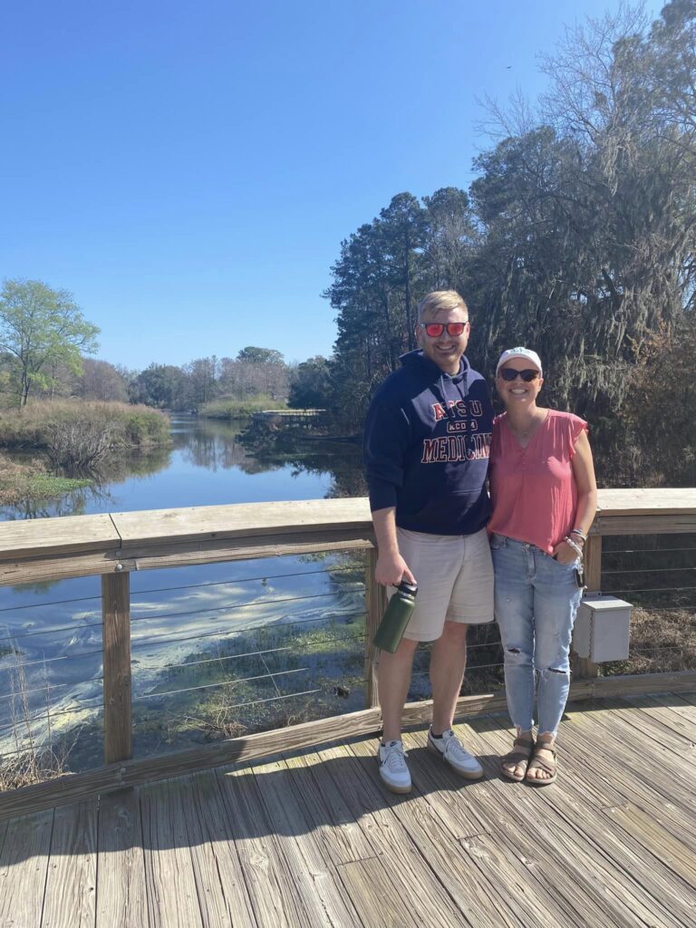 Brother and sister standing on bridge with marsh in behind