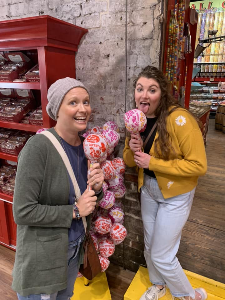 Two women acting like they are licking oversized lolipops