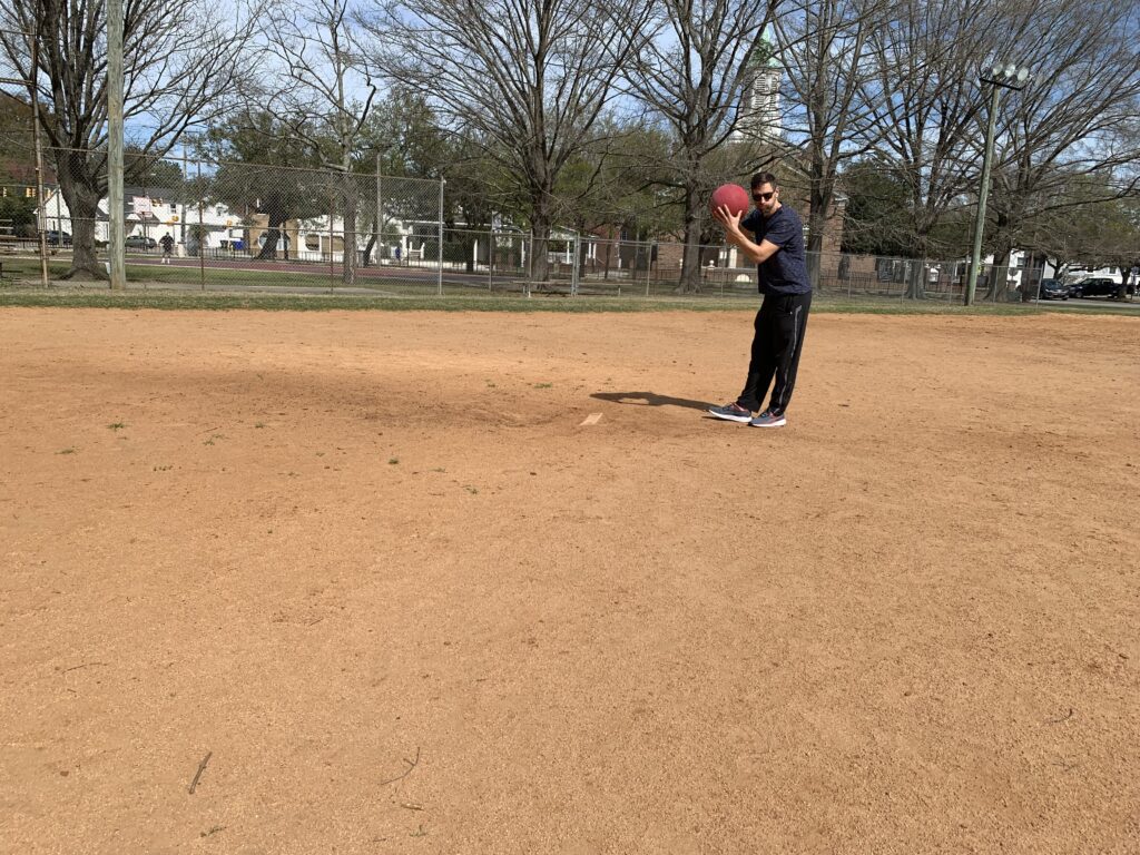 man gets ready to pitch a kickball on a baseball field