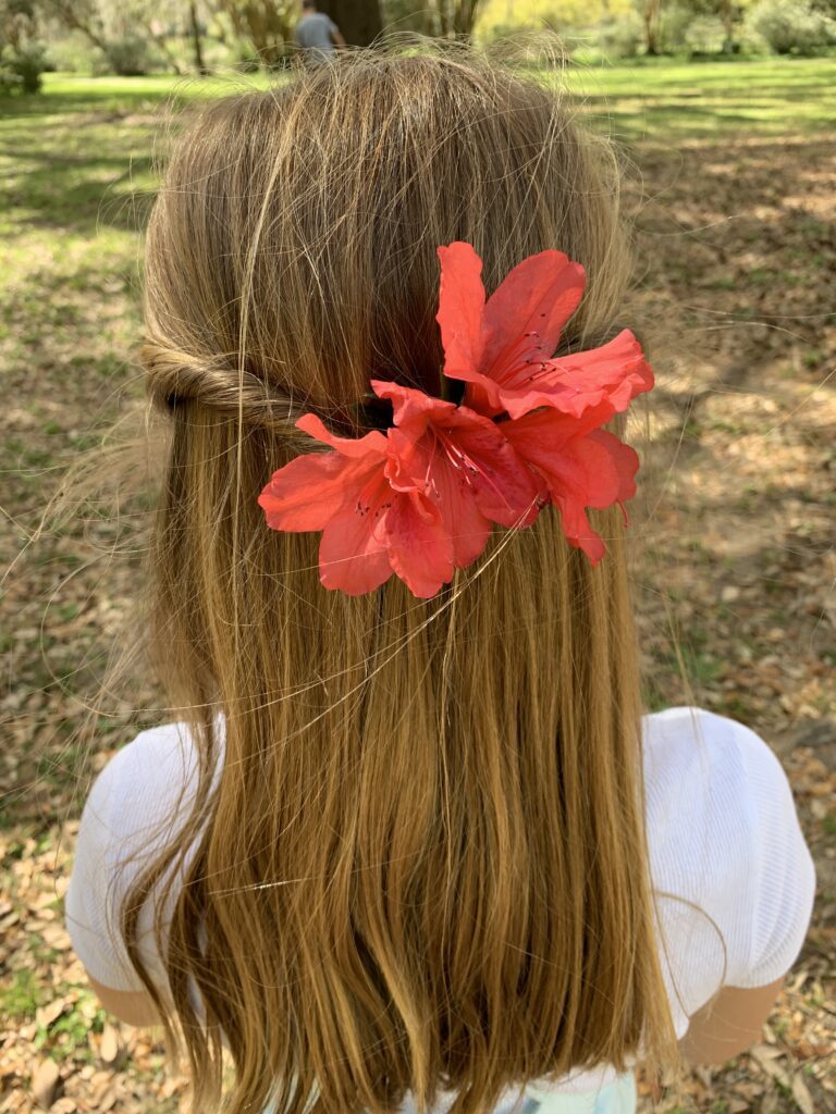 girl facing away from camera with Azalea flowers tucked into her hair